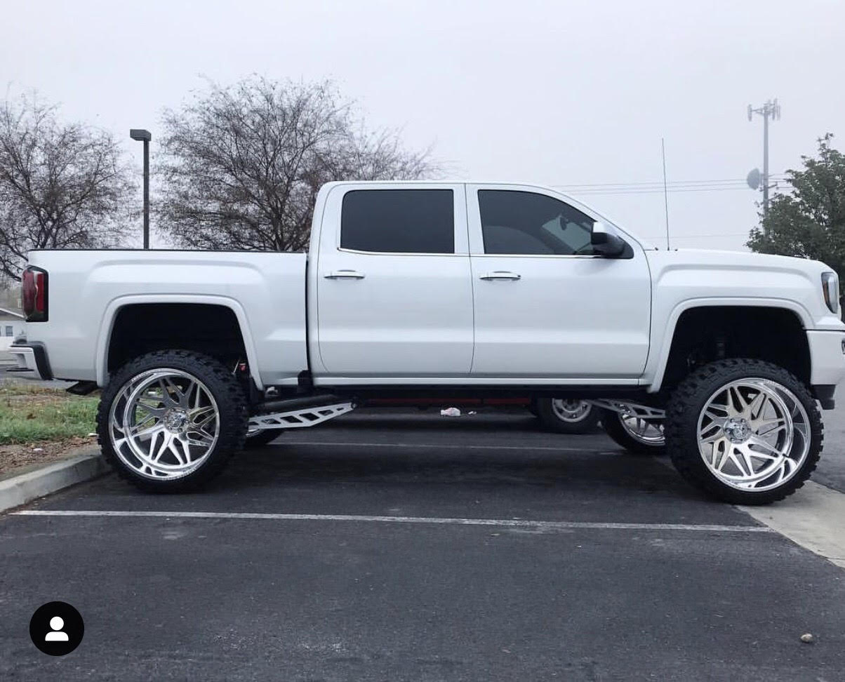 White truck with custom wheels and suspension